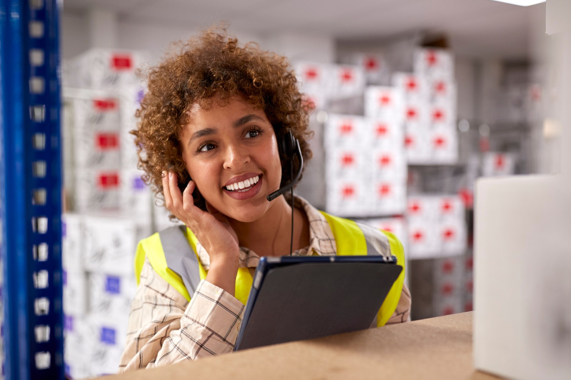Trabajadora con auriculares en un almacén de distribución logística utilizando una tableta digital