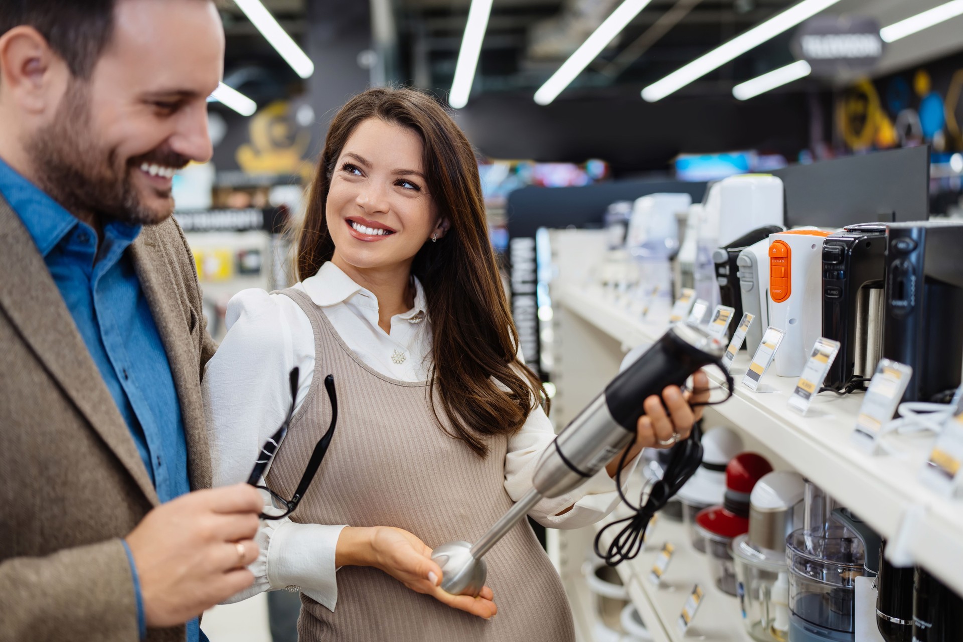 Compradores de parejas adultas jóvenes en una tienda de tecnología moderna.