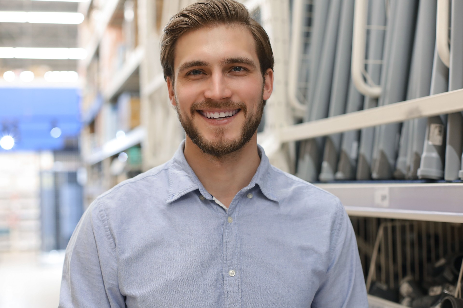 retrato de un joven trabajador sonriente de almacén que trabaja en un efectivo y llevar tienda al por mayor.